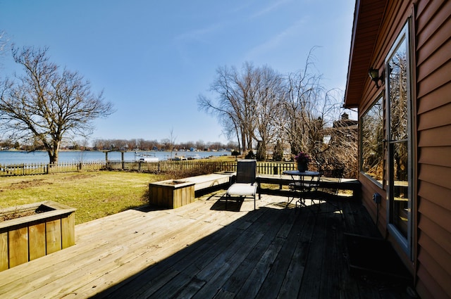 deck featuring a lawn, fence, and a water view