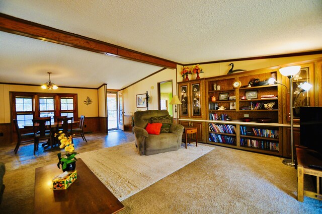 living area featuring wooden walls, a wainscoted wall, lofted ceiling with beams, ornamental molding, and a textured ceiling