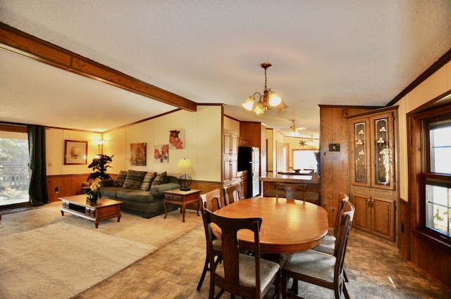 dining space with beam ceiling, wooden walls, a chandelier, and wainscoting