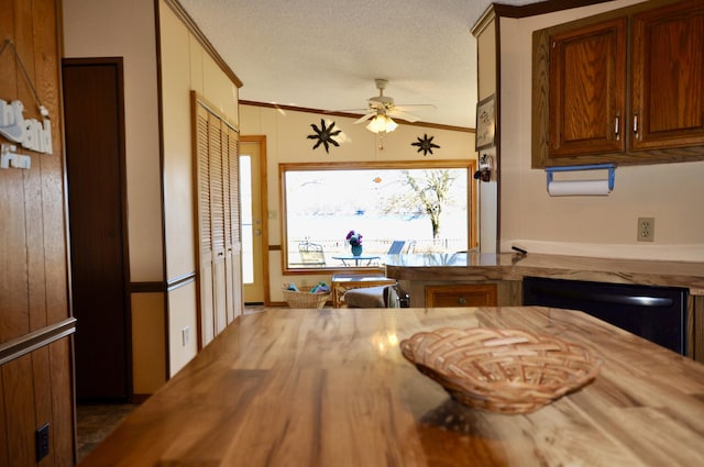 kitchen featuring butcher block counters, a textured ceiling, crown molding, and black dishwasher