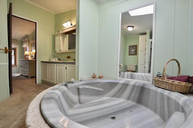 bathroom with a skylight, ornamental molding, and vanity