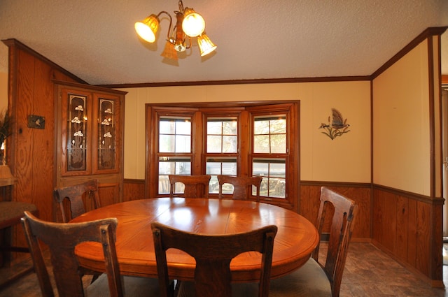 dining area with wainscoting, a textured ceiling, crown molding, and wood walls