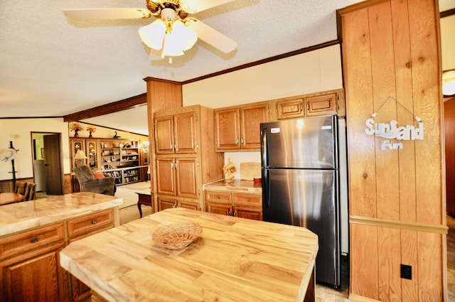 kitchen featuring lofted ceiling with beams, freestanding refrigerator, ornamental molding, a textured ceiling, and butcher block counters