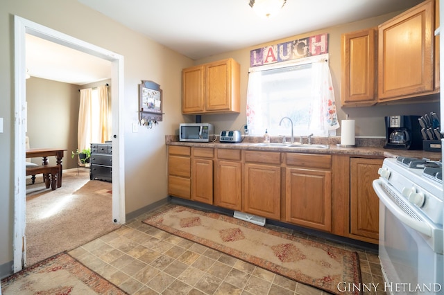 kitchen featuring stainless steel microwave, baseboards, white gas stove, light colored carpet, and a sink