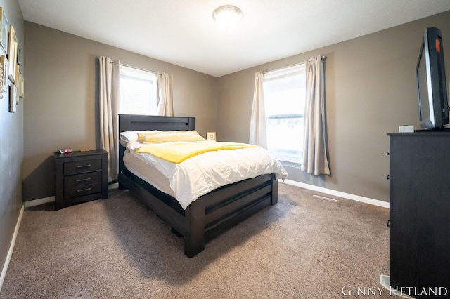 carpeted bedroom featuring multiple windows and baseboards