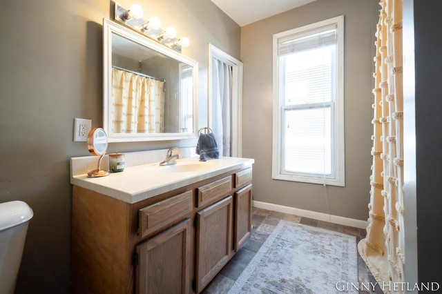 bathroom with toilet, vanity, and baseboards