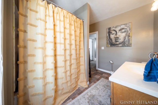 full bath featuring vanity, baseboards, and stone finish flooring