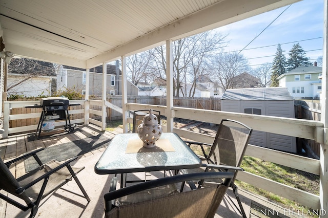 view of patio / terrace featuring a shed, a fenced backyard, an outdoor structure, outdoor dining space, and area for grilling