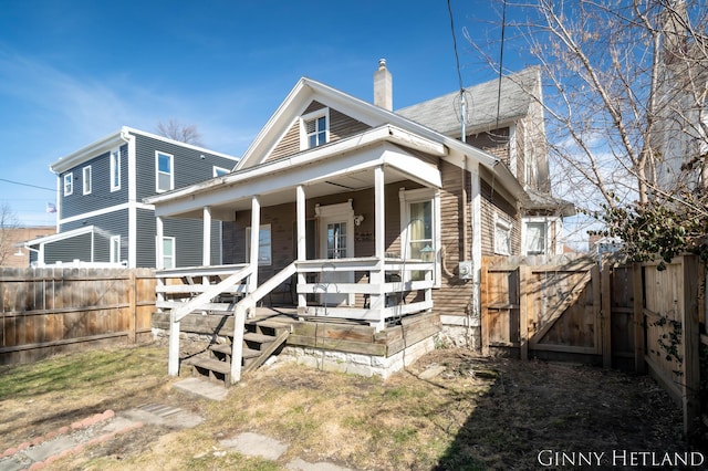 view of front of house with covered porch, a fenced backyard, a chimney, and a gate