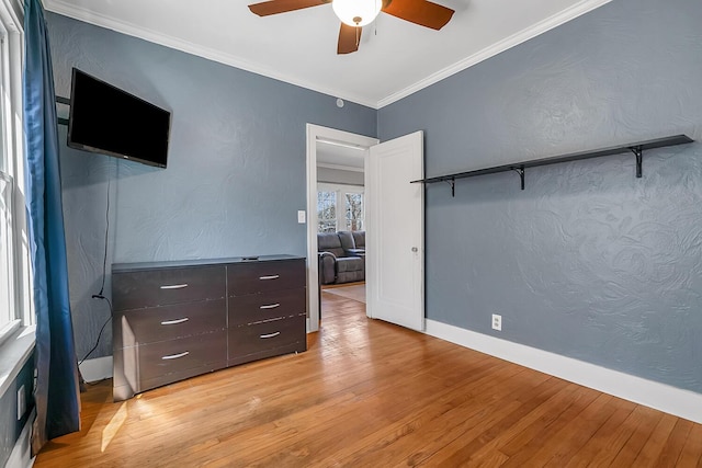 bedroom with baseboards, light wood finished floors, ceiling fan, ornamental molding, and a textured wall