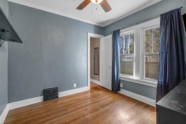 unfurnished room featuring visible vents, ornamental molding, and a textured wall