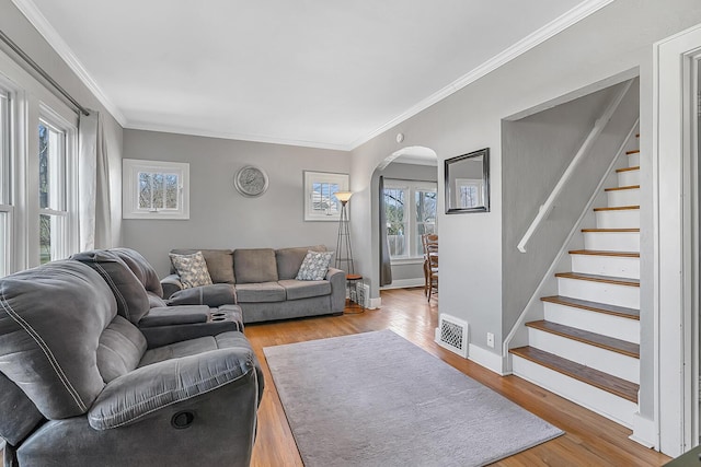 living area with arched walkways, visible vents, stairway, and wood finished floors