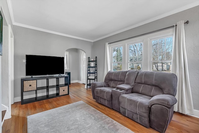 living room with baseboards, arched walkways, wood finished floors, and ornamental molding