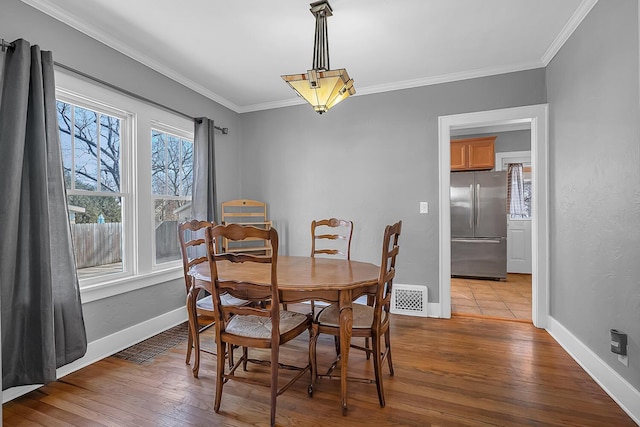 dining area with visible vents, crown molding, baseboards, and hardwood / wood-style flooring