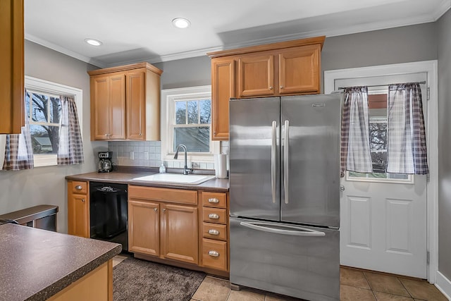 kitchen with black dishwasher, a healthy amount of sunlight, freestanding refrigerator, and a sink