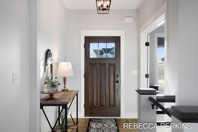 entryway featuring a notable chandelier, wood finished floors, and baseboards