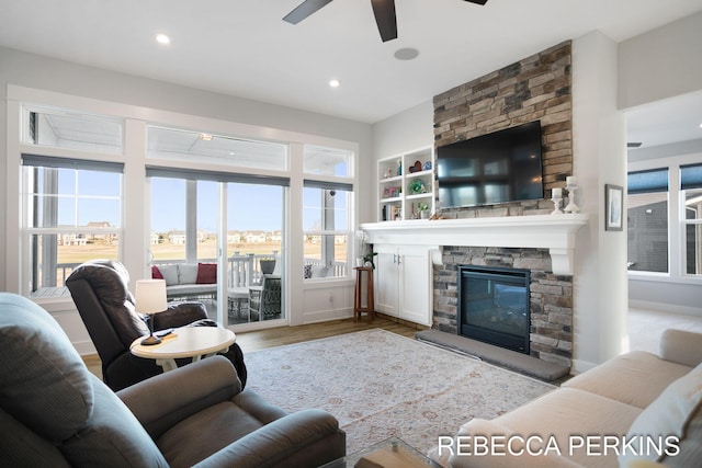 living room featuring a ceiling fan, wood finished floors, baseboards, recessed lighting, and a fireplace