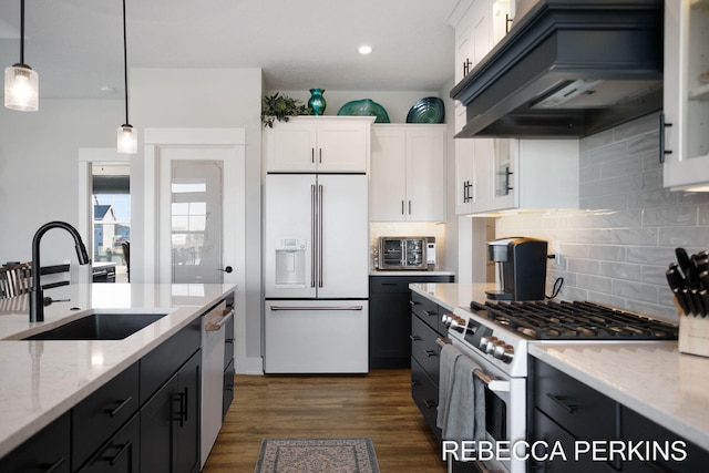 kitchen with custom exhaust hood, white appliances, white cabinetry, and a sink