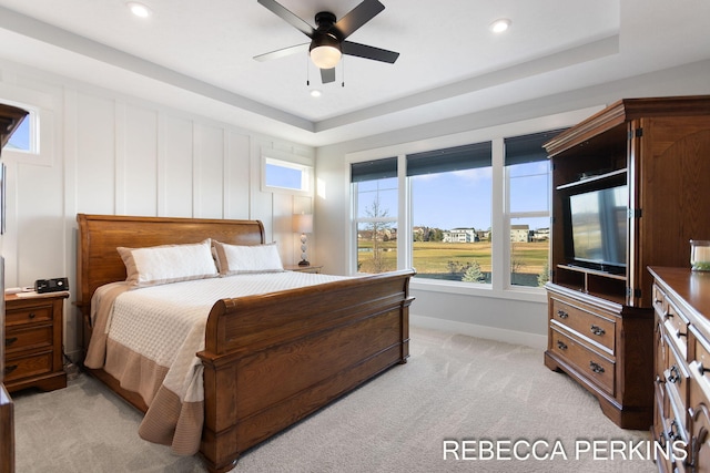 bedroom with a raised ceiling, a decorative wall, recessed lighting, and light colored carpet