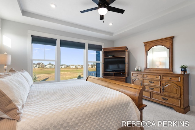 bedroom featuring a ceiling fan, a tray ceiling, recessed lighting, and light colored carpet