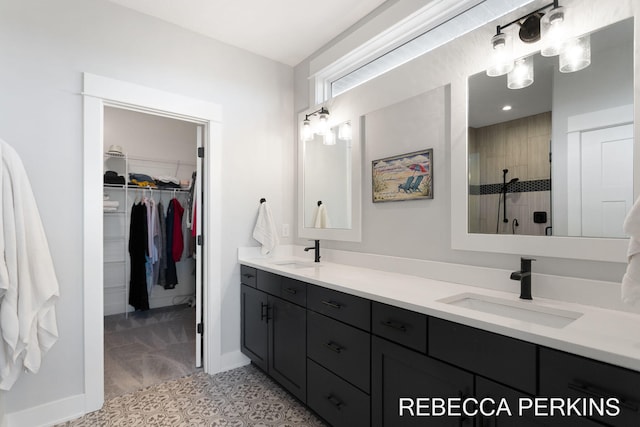 full bathroom with a walk in closet, double vanity, tiled shower, and a sink