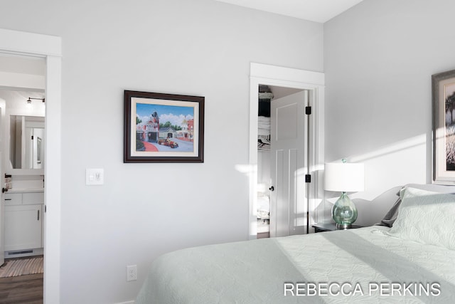 bedroom with connected bathroom, visible vents, and wood finished floors