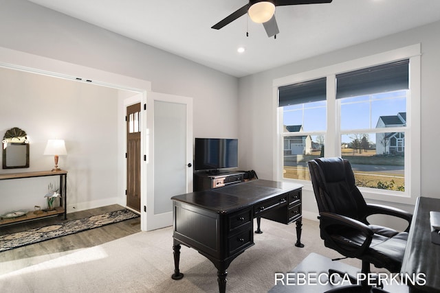 office space featuring light carpet, a healthy amount of sunlight, baseboards, and a ceiling fan