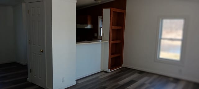 spare room with baseboards and dark wood-type flooring