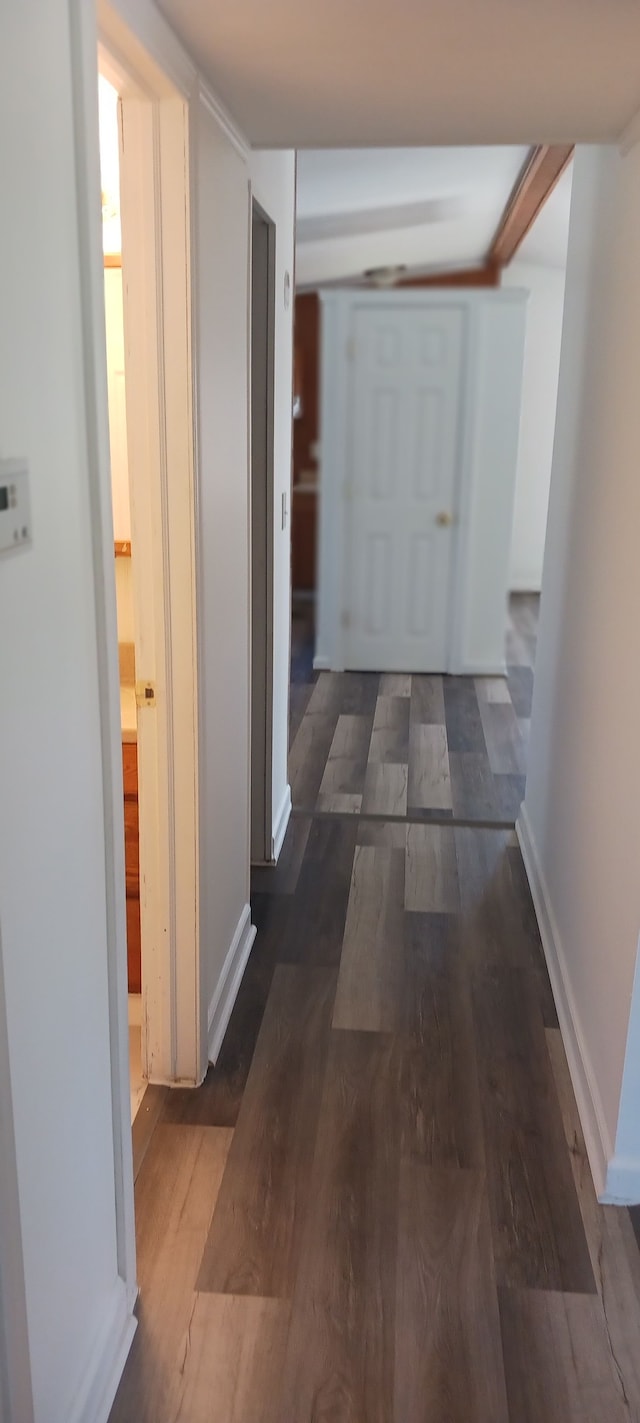 corridor with baseboards and wood finished floors