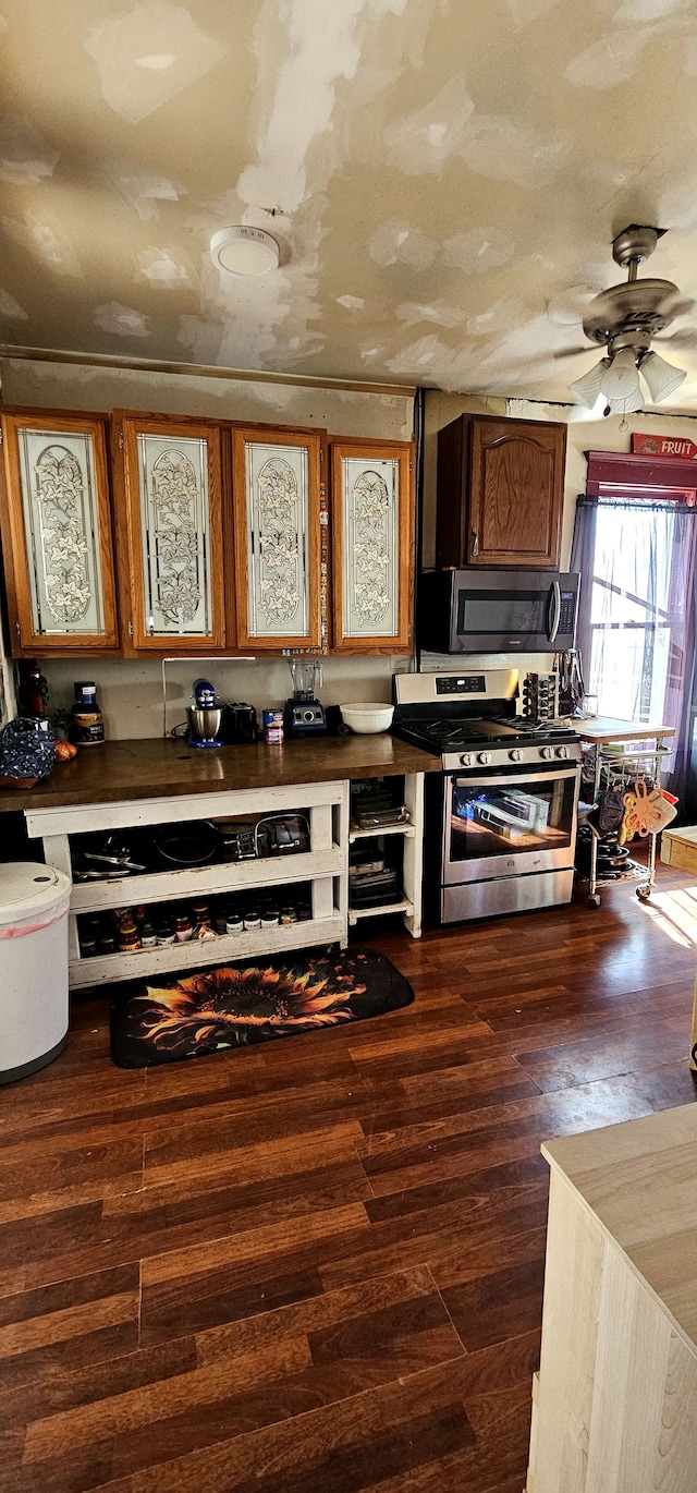 kitchen featuring stainless steel appliances, dark countertops, ceiling fan, and dark wood-style flooring