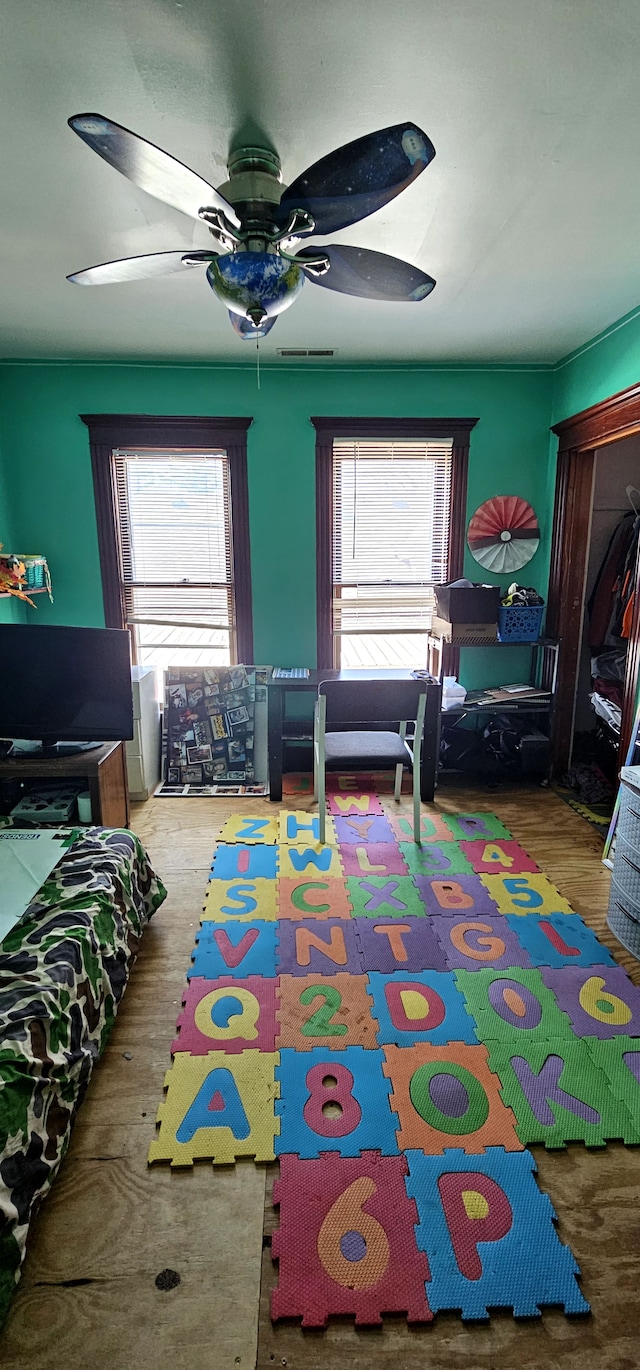 playroom with a wealth of natural light, visible vents, ceiling fan, and wood finished floors