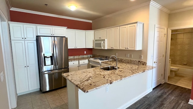 kitchen featuring ornamental molding, white appliances, a peninsula, and a sink