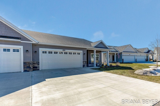 view of front of house with driveway, an attached garage, a shingled roof, a front lawn, and stone siding