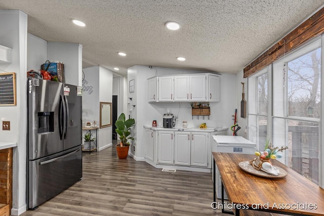 kitchen with white cabinets, refrigerator with ice dispenser, wood finished floors, and wooden counters