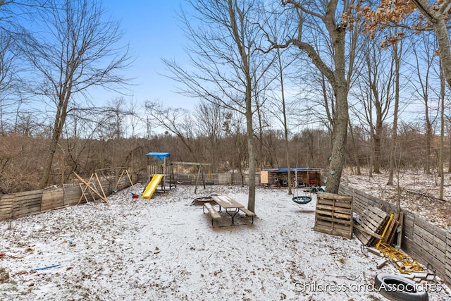 snow covered playground featuring a playground and fence