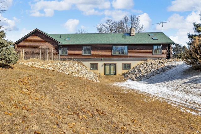 rear view of house featuring log siding, dirt driveway, and a chimney