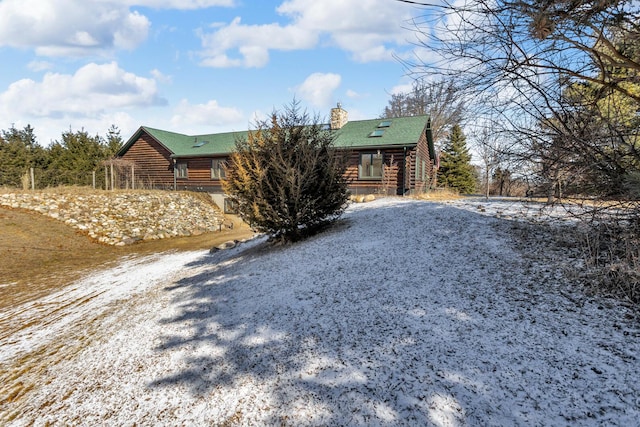 log home with driveway, log exterior, and a chimney