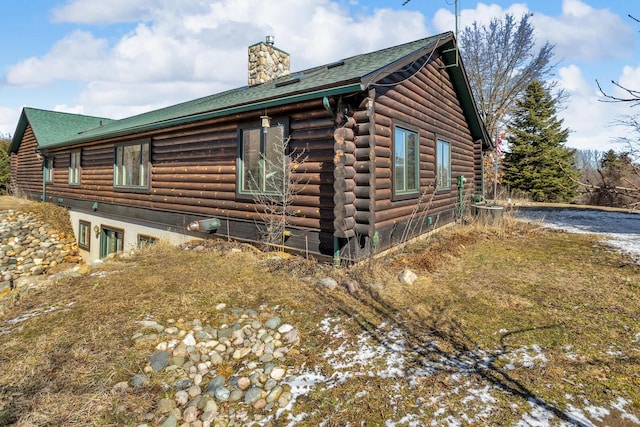 view of home's exterior with log siding and a chimney