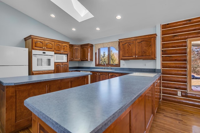 kitchen featuring white appliances, log walls, recessed lighting, a sink, and dark countertops