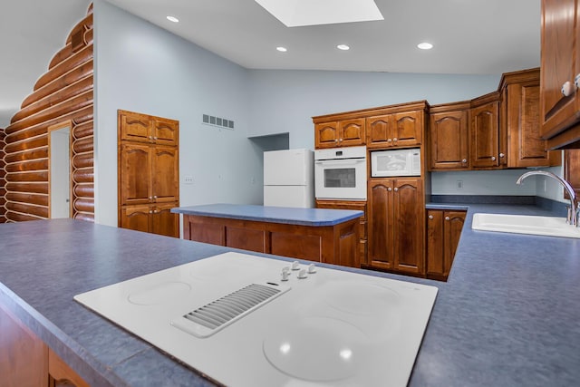 kitchen featuring white appliances, visible vents, vaulted ceiling with skylight, recessed lighting, and a sink