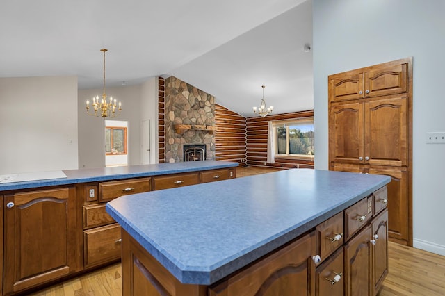 kitchen featuring an inviting chandelier, a fireplace, light wood-type flooring, and lofted ceiling