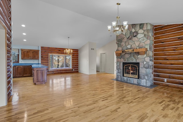 unfurnished living room with recessed lighting, a stone fireplace, a chandelier, and light wood finished floors