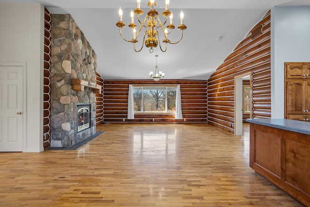 unfurnished living room with light wood-style floors, high vaulted ceiling, an inviting chandelier, and a fireplace