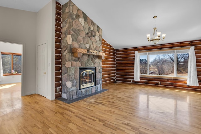 unfurnished living room with a stone fireplace, wood finished floors, a wealth of natural light, and log walls