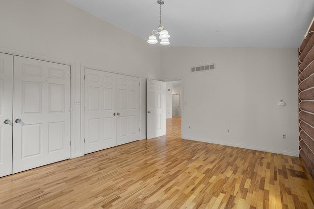 unfurnished bedroom featuring visible vents, light wood-style floors, high vaulted ceiling, and a notable chandelier