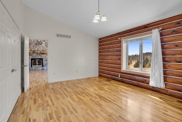 interior space with visible vents, a stone fireplace, light wood finished floors, baseboards, and a chandelier