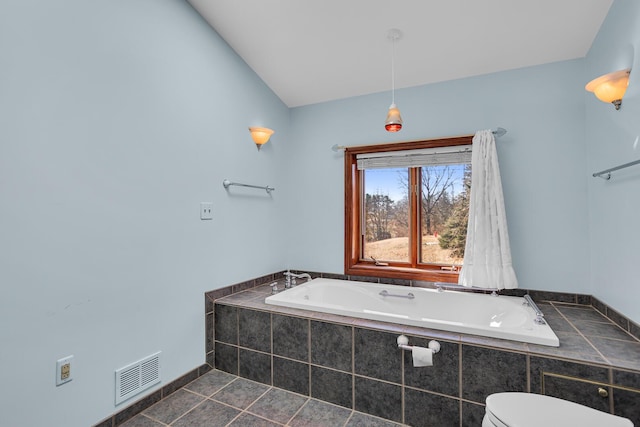 full bathroom with tile patterned flooring, visible vents, toilet, a garden tub, and vaulted ceiling