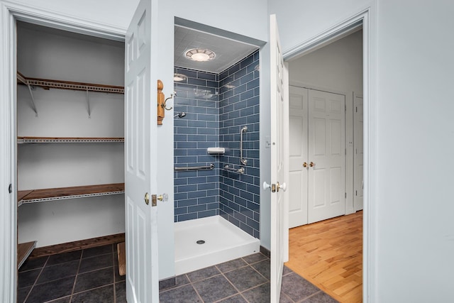 bathroom featuring tile patterned floors, a walk in closet, baseboards, and a shower stall