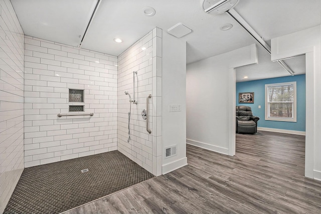 bathroom with wood finished floors, a tile shower, visible vents, baseboards, and recessed lighting