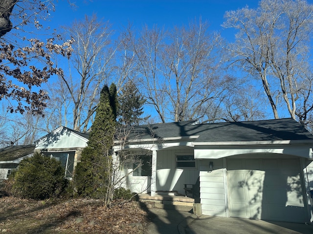 view of side of property featuring driveway, a shingled roof, and a garage